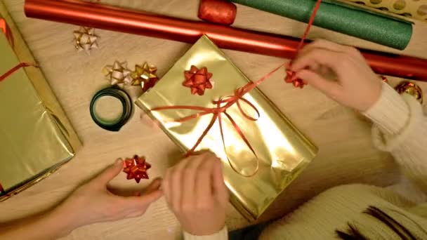 Hände zweier Frauen, die sorgfältig Weihnachtsgeschenke verpacken. Weihnachtstag. — Stockvideo