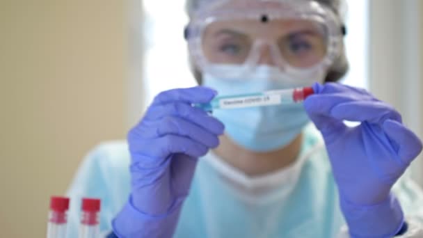 Cientista profissional usando óculos e uma máscara contém uma amostra de vacina contra o coronavírus 2019-ncov em sua mão. Parem a pandemia. — Vídeo de Stock