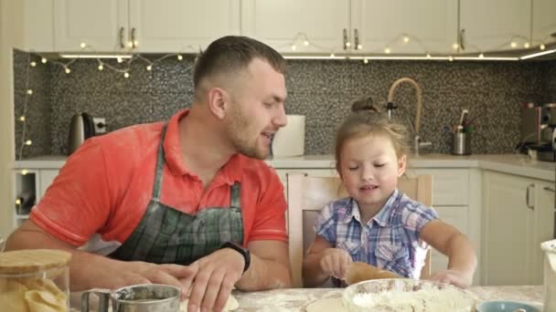父と娘5-6歳のナイフ生地キッチンで.父は偉大な愛と優しさで彼の子供を扱います. — ストック動画