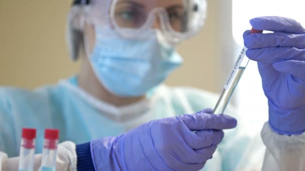 Professional female scientist wearing glasses and a mask holds a 2019-ncov coronavirus vaccine sample in her hand. Stop the pandemic. — Stock Video