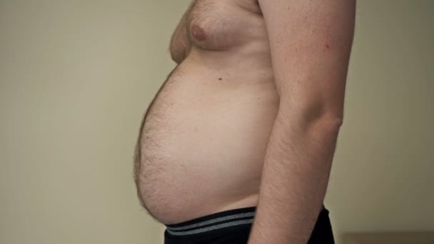 男人用他的手展示他腹部的脂肪褶皱。特写。肥胖和超重概念. — 图库视频影像