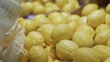 Kadın eli, limonları ip torbasına koyar. Yakın plan. Çevre dostu bu torba ile alışveriş.