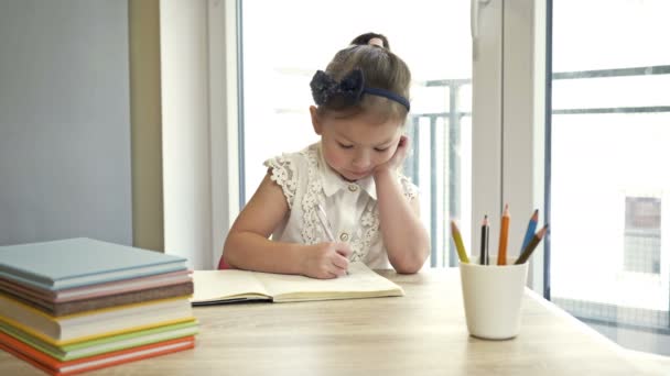 Petite écolière du primaire qui fait ses devoirs. Un enfant mignon apprend tout seul. Retour à l'école. — Video