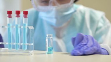 Koruyucu giysili laboratuar teknisyeni bir şişe madde bırakıyor. Çalışırken hatalar.