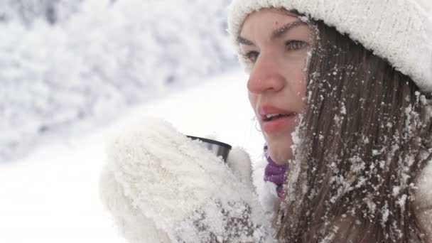 Portrait d'une belle jeune femme qui boit un verre chaud après un combat de boule de neige. — Video