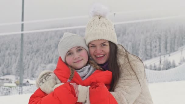 Bir kış manzarasının arka planında genç kızıyla birlikte genç bir kadının aile portresi.. — Stok video