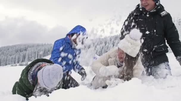 Grupo de amigos alegremente rocía nieve el uno sobre el otro. Un maravilloso día de invierno. En el fondo de un bosque nevado. — Vídeos de Stock