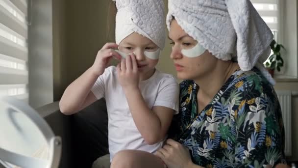 Giovane donna e la sua bambina stanno facendo trattamenti di bellezza dopo una doccia. A entrambi piace guardarsi allo specchio.. — Video Stock