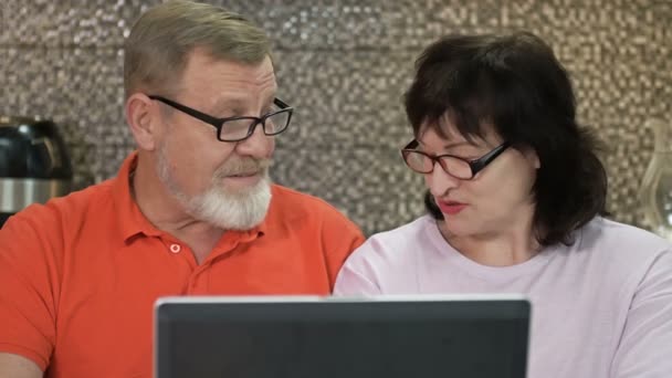Üst düzey çift evde dizüstü bilgisayar kullanarak online alışveriş yapıyor, internette sörf yapıyor.. — Stok video