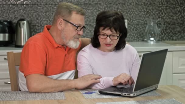 Veselý manželský pár používá notebook doma pro on-line nakupování. Nakupování během pandemie koronaviru. — Stock video