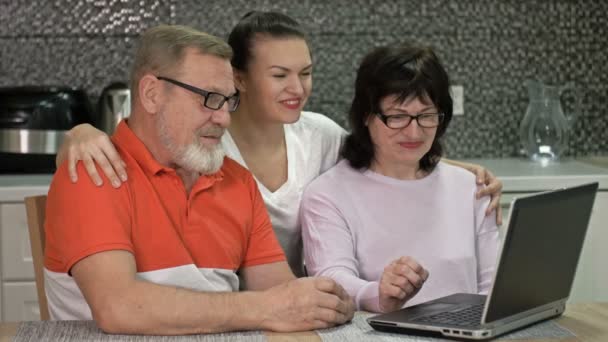 Egy idős pár és a felnőtt lányuk kommunikálnak valakivel az interneten keresztül. Modern technológiák, új lehetőségek. — Stock videók