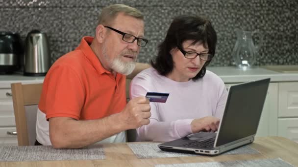Дружелюбная супружеская пара использует ноутбук дома для интернет-покупок. Покупки во время пандемии коронавируса. — стоковое видео