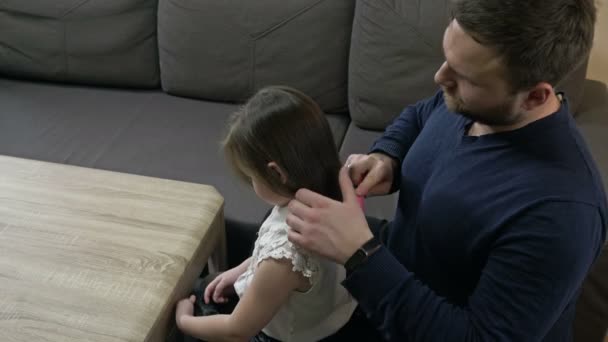 Opiekuńczy tata próbuje czesać swoje córki długimi włosami. — Wideo stockowe