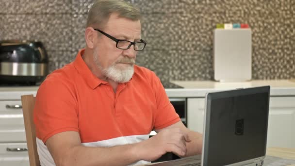 Un uomo anziano si siede davanti a un computer portatile. E 'sconvolto per qualcosa. Problematiche. — Video Stock