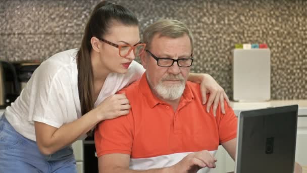 Urocza brunetka i jej ojciec gapią się uważnie na ekran laptopa. Dobre wieści powodują burzę pozytywnych emocji.. — Wideo stockowe