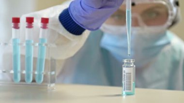 Koruyucu gözlüklü ve maskeli profesyonel kadın bilim adamı laboratuvarda reaktörlerle deney yapıyor. Koronavirüse karşı aşı üretimi.