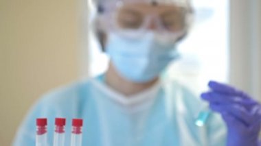 Bir uzman, koruyucu giysi, eldiven, gözlük ve maskeyle temiz bir laboratuvarda kovid 19 koronavirüs aşısı üzerinde çalışıyor..