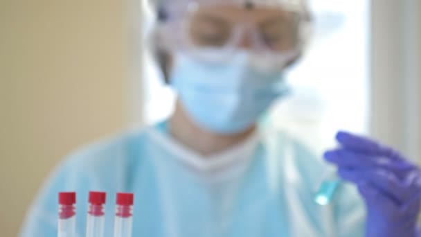 Um especialista trabalha em uma vacina contra o coronavírus covid 19 em um laboratório limpo com um terno de proteção, luvas, óculos e uma máscara. — Vídeo de Stock