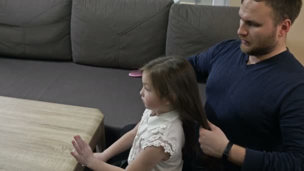 Middle-aged man tries to braid his little daughters braids. Hes bad at it. Fathers day. — Stock Video