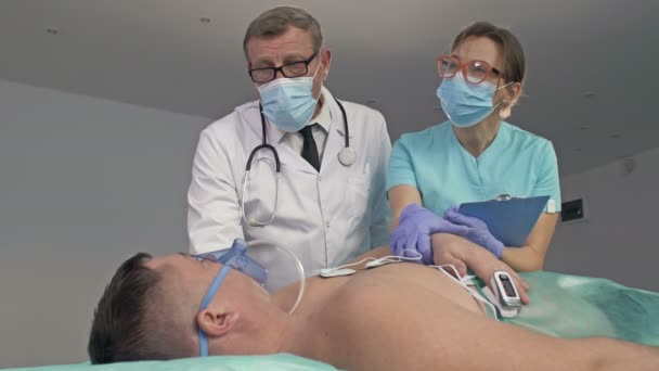 Врачи, осматривающие пациента на кровати в отделении скорой помощи больницы. — стоковое видео