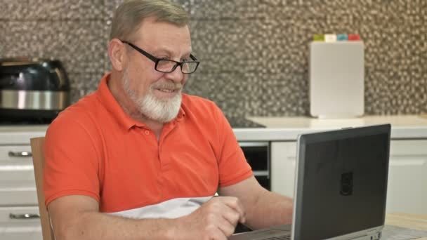 Bărbatul de vârstă de pensionare urmărește îndeaproape ce se întâmplă pe ecranul laptopului . — Videoclip de stoc