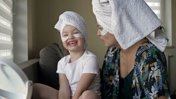 Young woman and her little daughter are doing beauty treatments after a shower. Both are in a great mood. — Stock Video