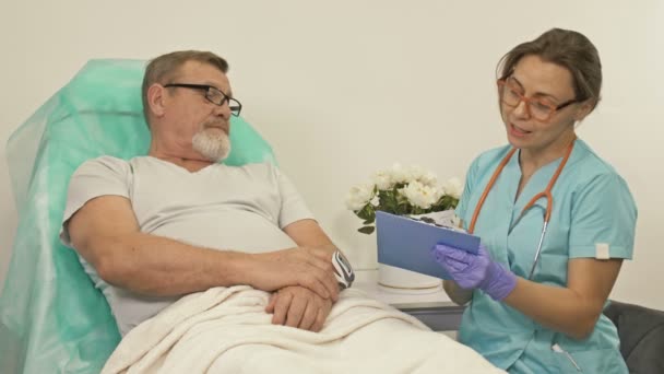 Lekarz rozmawia ze starszym pacjentem na oddziale szpitalnym.. — Wideo stockowe