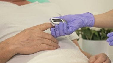 Doktorlar lateks eldivenler verip koronavirüsünden şüphelenilen bir hastanın kanındaki oksijen seviyesini ölçüyorlar. Yakın plan..