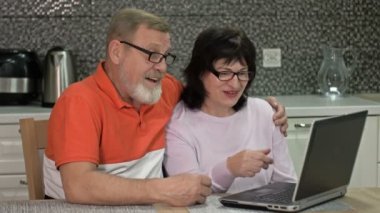 Neşeli evli çift internet üzerinden biriyle iletişim kuruyor. Modern teknolojiler, yeni fırsatlar.