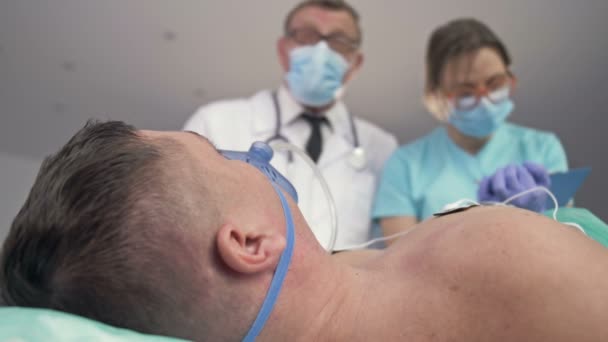 Lekarze badający pacjenta na łóżku na ostrym dyżurze szpitala. — Wideo stockowe