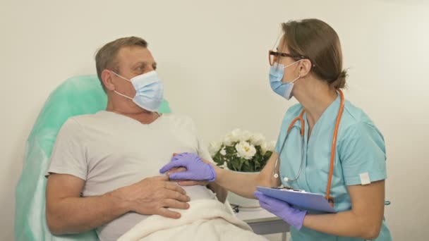 Doktor mluví se starším pacientem na nemocničním oddělení. Žena povzbuzuje pacienta. — Stock video