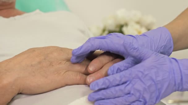 Κοντινό πλάνο. Οι γιατροί κρατιούνται χέρι χέρι ενός ηλικιωμένου ασθενή. χειρονομία υποστήριξης. — Αρχείο Βίντεο
