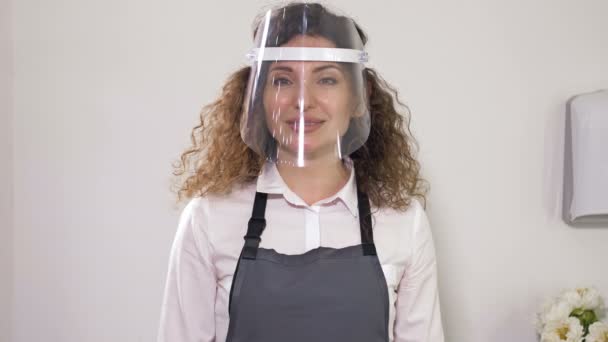 Portræt af en kvindelig sælger i en cafe iført en plastbeskyttelsesmaske. Handelsregler under coronaviruspandemien. – Stock-video
