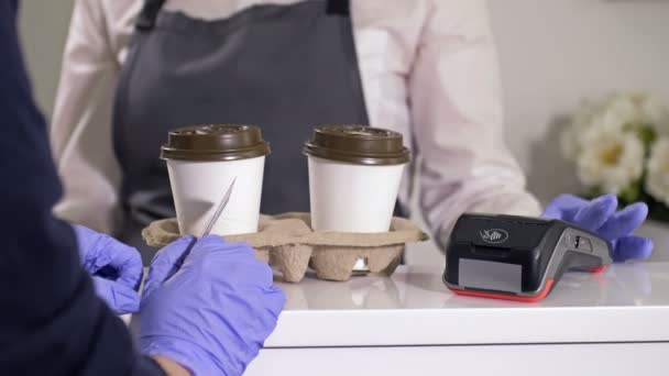 De koper neemt twee wegwerpkopjes koffie en betaalt de aankoop met een betaalkaart. Fast food in het gezicht van de coronavirus pandemie. Afhaalhandel. — Stockvideo
