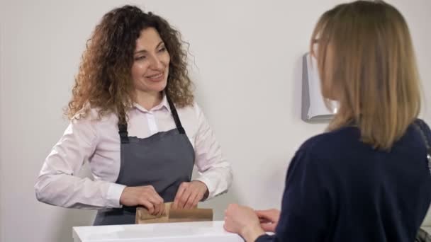 Pequeña empresa. Comercio de comida para llevar. Un vendedor que atiende a un cliente en un café. — Vídeos de Stock