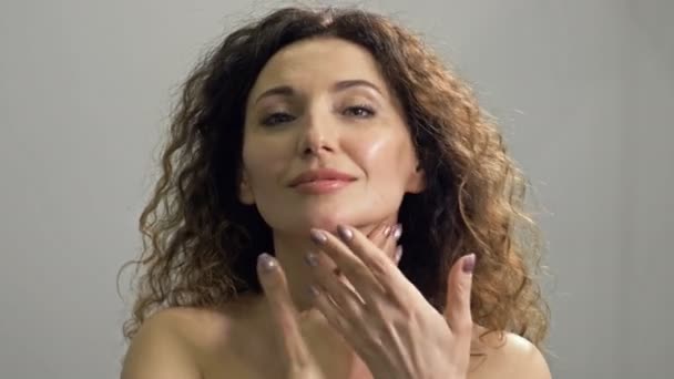 Mooie vrouw van middelbare leeftijd masseert haar gezicht en nek met lichte bewegingen. Dagelijkse huidverzorging. — Stockvideo
