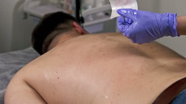 Close-up. Mestre realiza procedimento de depilação no spa de beleza. Depilação de cabelo nas costas de um homem. — Vídeo de Stock