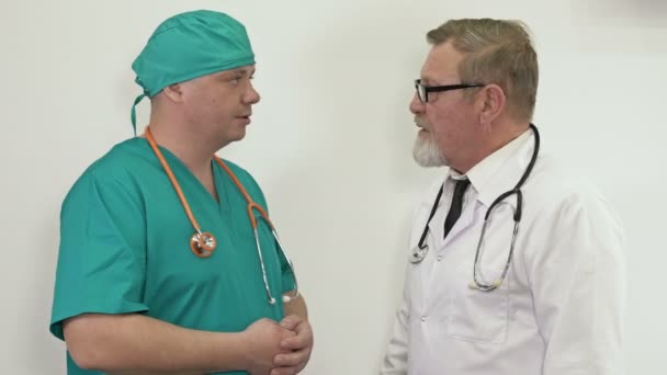 Зрілий лікар обговорює з молодим колегою в лікарняному коридорі . — стокове відео
