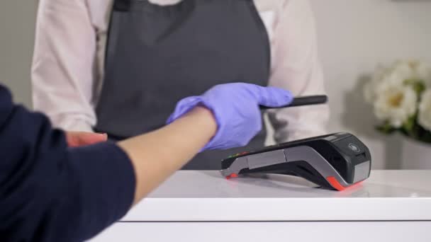 Genehmigungsverfahren für Handyzahlungen. Kontaktloses Bezahlen bei Einkäufen mit dem Smartphone. Käufer mit Latexhandschuhen. Vorsicht während der COVID-19-Pandemie. — Stockvideo