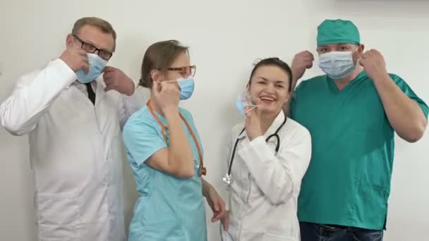 Un grupo de médicos se quitan las máscaras médicas y aplauden. La pandemia del COVID-19 ha sido derrotada. — Vídeos de Stock