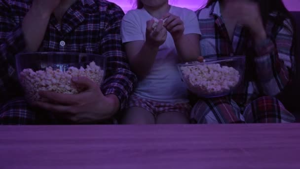 Une jeune famille avec une petite fille regarde la télé, tout le monde mange du pop-corn ensemble. Mise en quarantaine pendant la pandémie de Covid-19. — Video