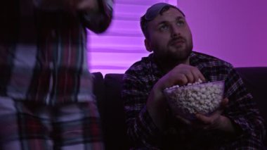 Güzel, birbirine aşık genç bir çift yan yana oturmuş patlamış mısır yiyor ve geceleri televizyon izlerken eğleniyorlar. Covid-19 salgını sırasında ev karantinası.