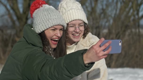 Joven mujer y su hija adolescente tomar una selfie durante un paseo de invierno. — Vídeos de Stock