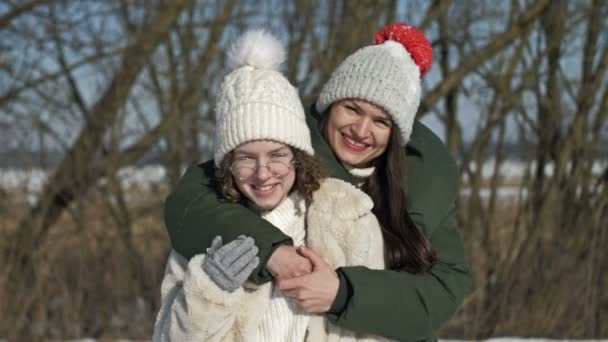 Mamá y una hija adulta o dos hermanas se están divirtiendo durante una caminata de invierno, y alguien les está tirando nieve.. — Vídeos de Stock