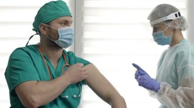 Hemşire bir doktora koronavirüs aşısı yapıyor..