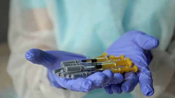 Hands of a nurse in protective latex gloves hold syringes prepared for vaccination. Close-up. — Stock Video