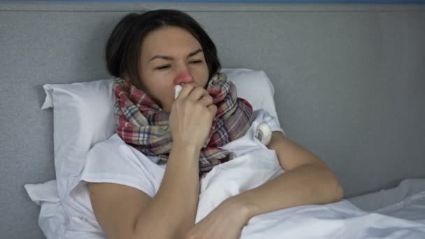 Jeune femme malade se trouve au lit et mesure la température. Elle tousse, frissonne, a le nez qui coule. Symptômes de grippe, de rhume ou de coronavirus. — Video