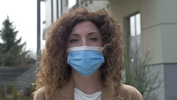 COVID-19 Pandemia. Kobieta w średnim wieku na pustynnej ulicy miasta w masce ochronnej przed rozprzestrzenianiem się zakażenia koronawirusem. Zamknięcie.. — Wideo stockowe