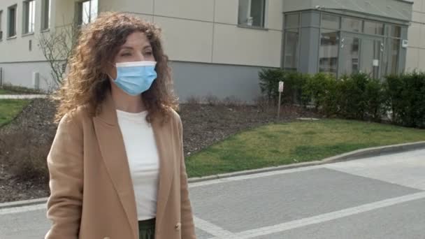 Een vrouw met een beschermend masker loopt door een verlaten straat. Afsluiting door de Covid-19 pandemie. — Stockvideo