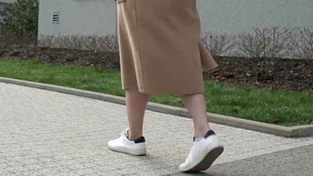 Primer plano. Las piernas de las mujeres en zapatillas blancas están caminando por la calle de la ciudad. Aspecto urbano casual femenino. Estilo de vida saludable. — Vídeos de Stock